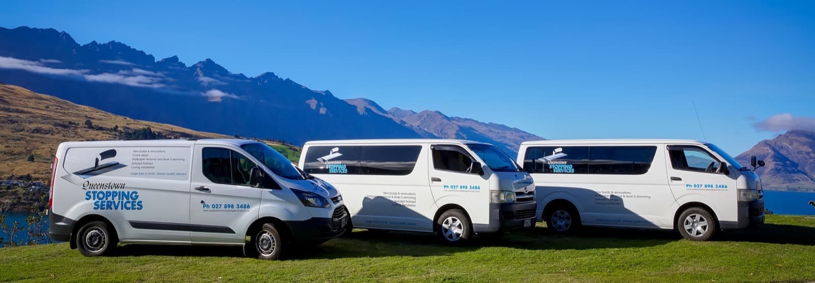 Queenstown Stopping Services vans parked with the Remarkables mountain range behind